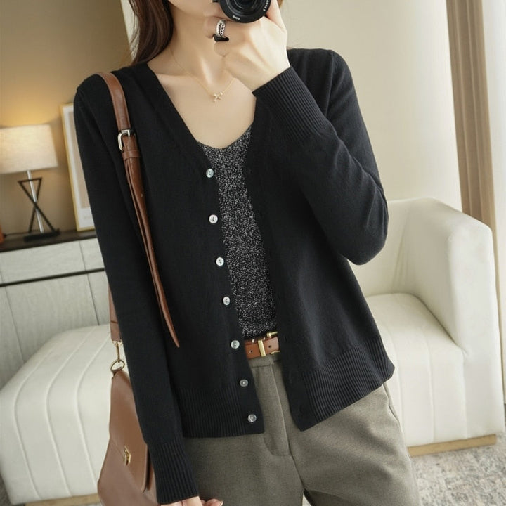 Frau in schwarzem Cardigan und grauem Top, braune Hose, modisch, lässig, Innenraum.