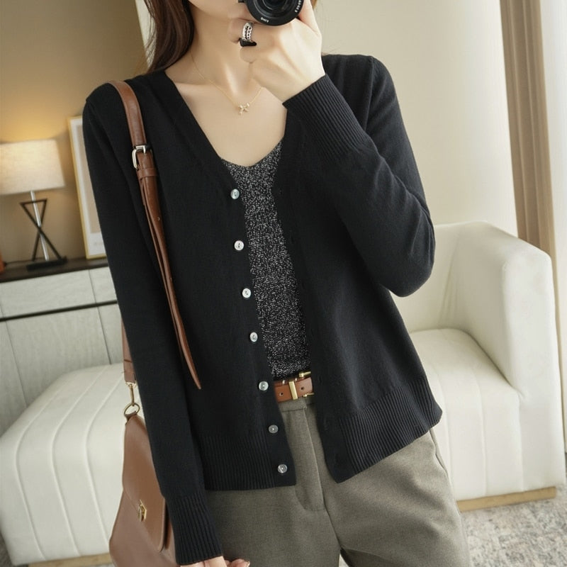 Frau in schwarzem Cardigan und grauem Top, braune Hose, modisch, lässig, Innenraum.