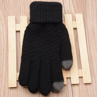 Schwarzer Strickhandschuh mit grauen Fingerspitzen auf Holzuntergrund, Wintermode Accessoire.