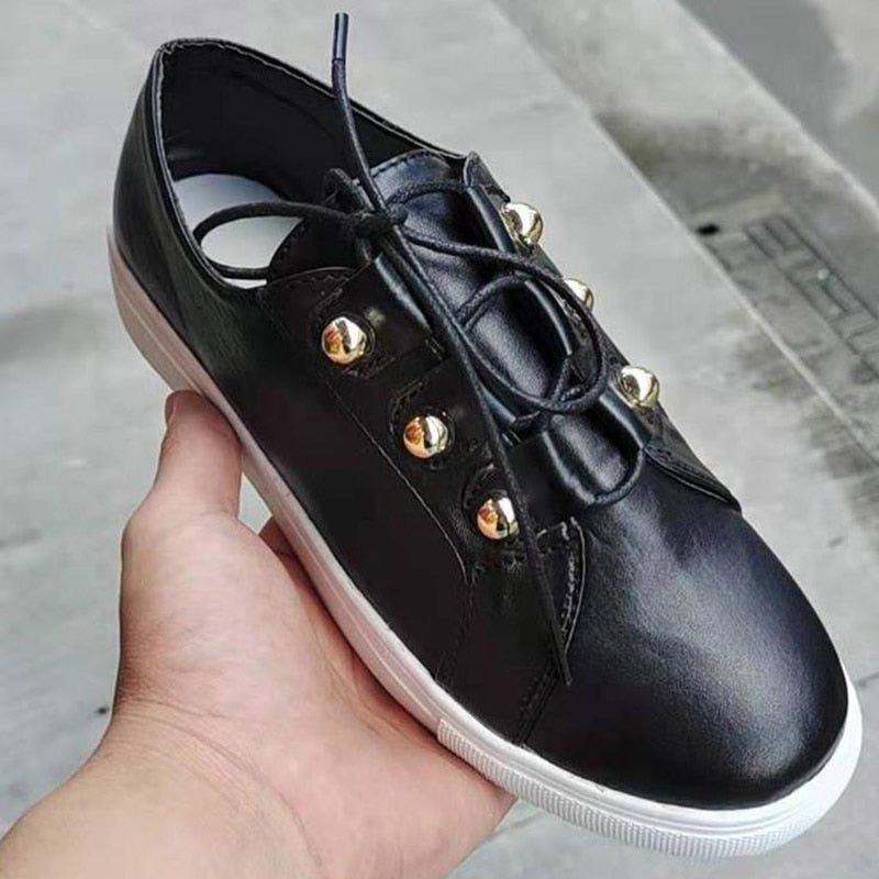 Schwarzer Ledersneaker mit goldenen Nieten, weißer Sohle, modisch, bequem, Unisex.