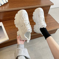 Weiße Damen-Sneaker, stilvoll und bequem, auf Holztreppe, modische Freizeitschuhe.