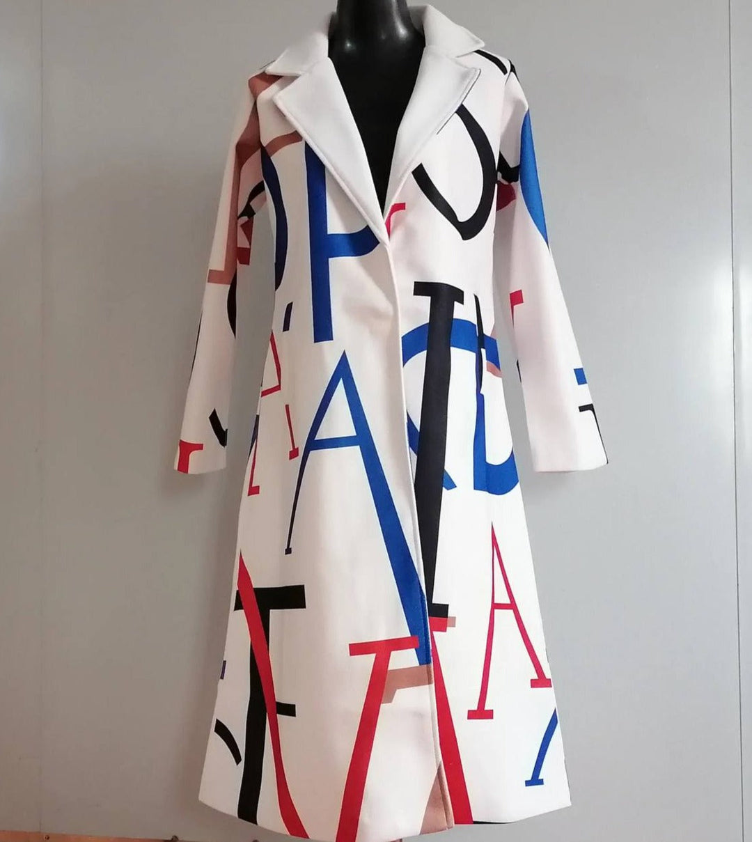 Weißer Mantel mit buntem Buchstabenmuster, Damenmode, Herbstkollektion, stilvoller Look.
