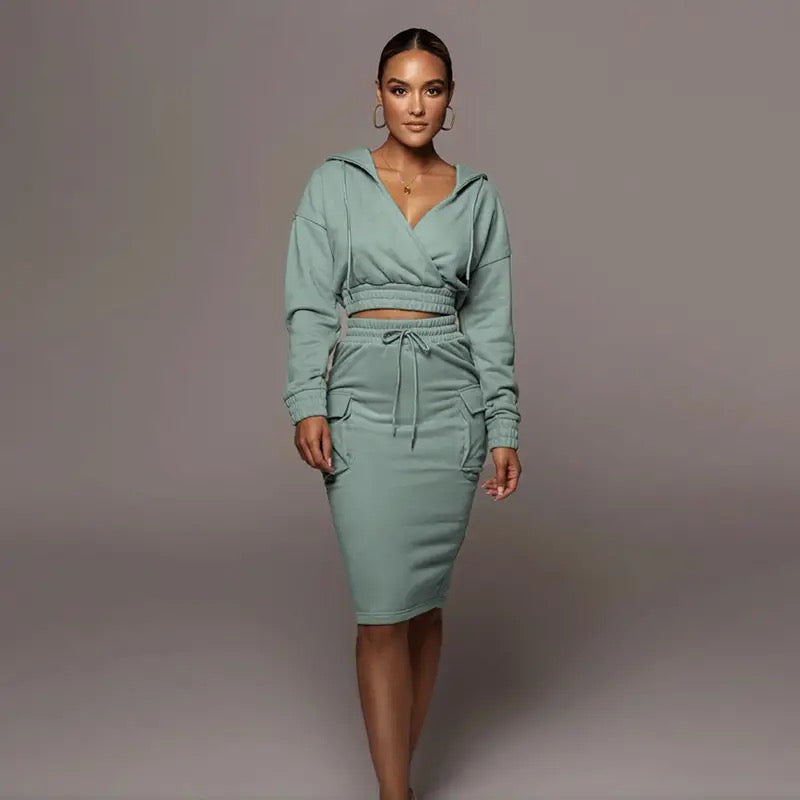 Frau in grünem Kapuzenkleid, tailliert, langärmelig, modisch, Freizeitkleidung, elegant.