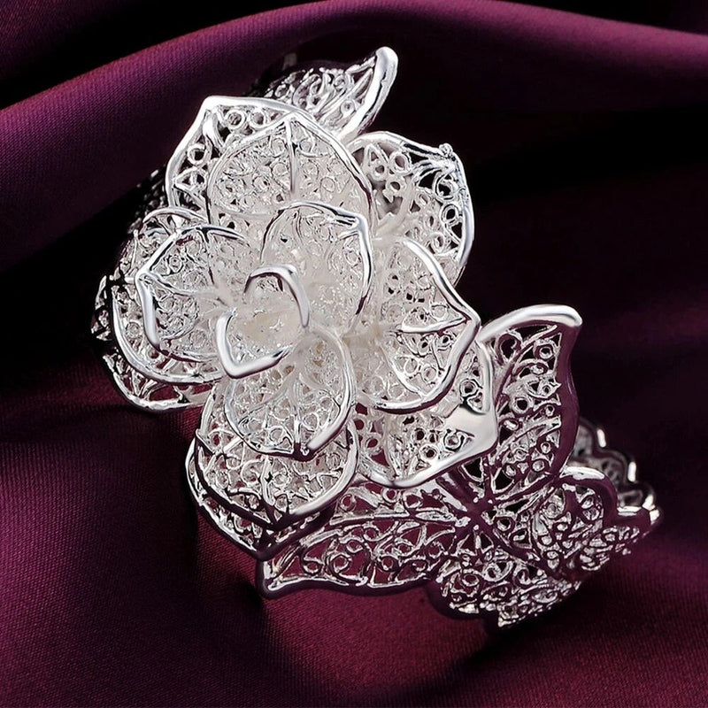 Silberne filigrane Blumenbrosche auf violettem Stoff, elegantes Schmuckdesign.