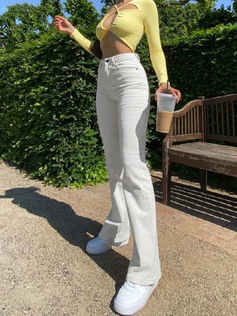 Frau in weißer Schlaghose und gelbem Oberteil, hält Eiskaffee, modisch, Sommeroutfit.