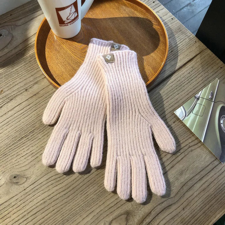 Rosa Strickhandschuhe aus Wolle auf Holztisch, Damenmode, Winteraccessoire, stilvoll und warm.