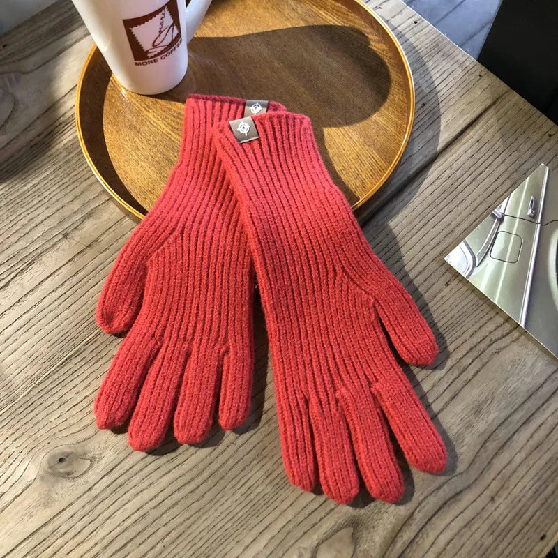 Rote Strickhandschuhe aus Wolle auf Holztisch, modisch, warm, ideal für Winterkleidung.