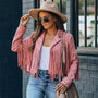 Frau in rosa Fransenjacke, Sonnenbrille und Hut, lässiger Streetstyle-Look.