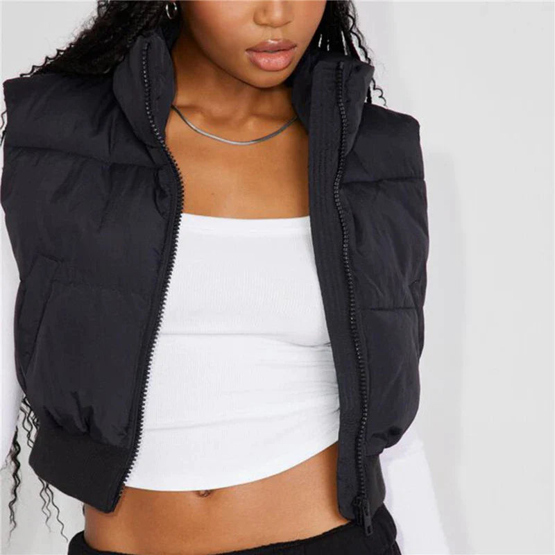 Frau trägt schwarze Steppweste, weißes Top, silberne Halskette, modisch, lässig.