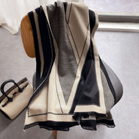 Schwarz-beige Kaschmirschal mit geometrischem Muster auf Holzstuhl, elegantes Accessoire.