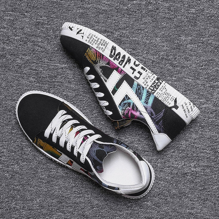 Schwarze Sneaker mit buntem Print, Textmuster, weiße Sohle, modische Freizeitschuhe.