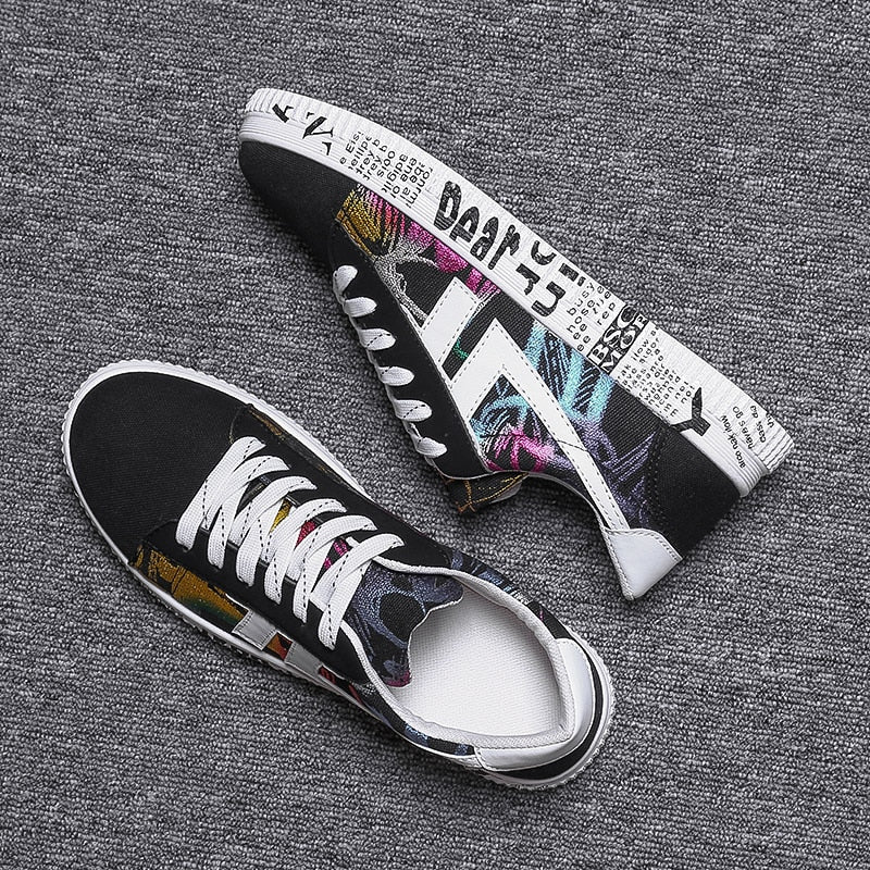Schwarze Sneaker mit buntem Print, Textmuster, weiße Sohle, modische Freizeitschuhe.