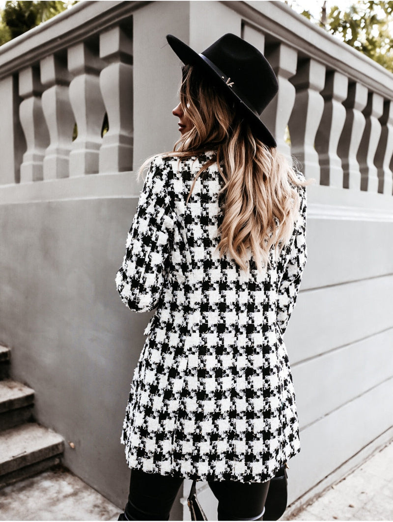 Frau im schwarz-weiß karierten Mantel und schwarzem Hut, stilvolle Herbstmode, Rückansicht.