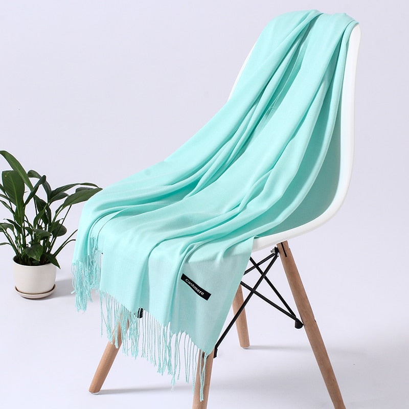 Hellblauer Schal aus Kaschmir auf weißem Stuhl, elegantes Design, weiches Material, Wohnzimmer.