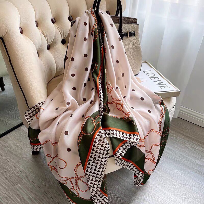 Seidenschal mit Kettenmuster und Polka-Dots, beige und grün, auf Sessel drapiert.