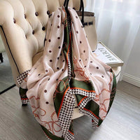 Seidenschal mit Kettenmuster und Polka-Dots, beige und grün, auf Sessel drapiert.