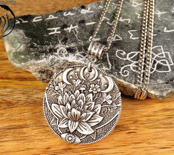 Silberanhänger mit Lotusblume und Mondsichel, filigranes Design, auf Holzhintergrund.