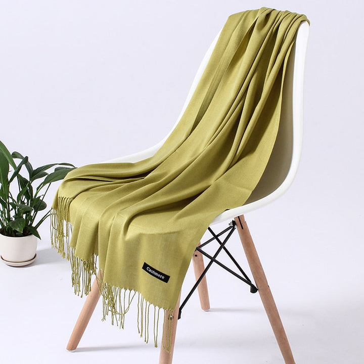 Grüner Kaschmirschal auf weißem Stuhl, weiches Material, modisches Accessoire, Wohnzimmer.