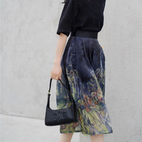 Frau in schwarzem Oberteil und bedrucktem Rock mit schwarzer Designer-Handtasche.