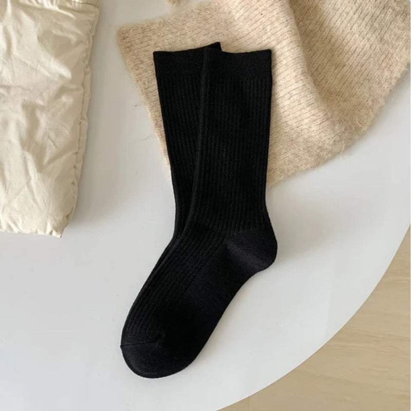 Schwarze Baumwollsocken auf weißem Tisch, modisch, bequem, für Damen und Herren.