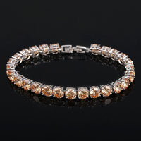 Silbernes Tennisarmband mit runden, champagnerfarbenen Zirkonia-Steinen auf schwarzem Hintergrund.