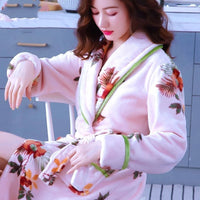 Frau im rosa Bademantel mit Blumenmuster, weiches Material, gemütlich, modisch, Damenbekleidung.