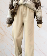 Beige Hose, brauner Pullover, Umhängetasche, Marmorhintergrund, modisches Outfit.