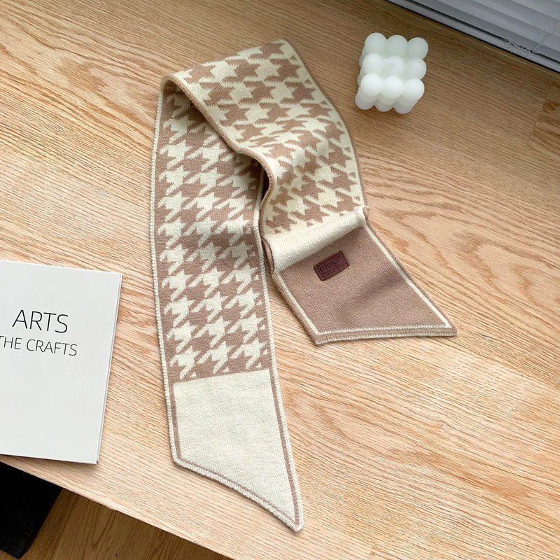 Beige-weißer Hahnentritt-Schal aus Wolle auf Holztisch, modisches Accessoire.