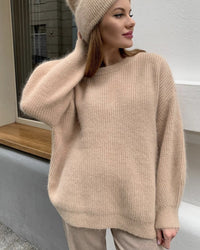 Frau in beigem Strickpullover und Mütze, gemütliche Wintermode, elegantes Design.