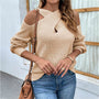 Frau in beige Strickpullover mit Schulterfrei-Design, blaue Jeans, braune Umhängetasche.