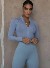 Frau in hellblauem Sportanzug, Reißverschluss, langärmelig, elegantes Design, Fitnessmode.