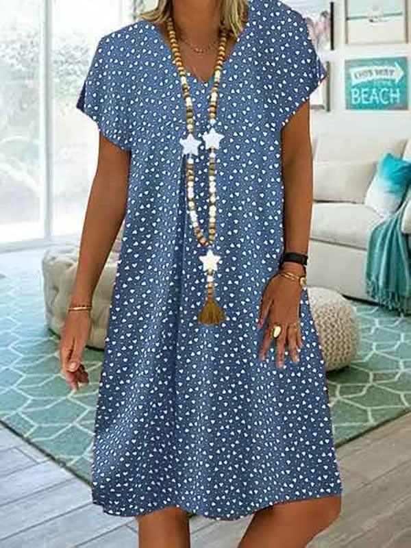 Frau in blauem Sommerkleid mit weißen Punkten, Holzperlenkette, lässiger Strandlook.