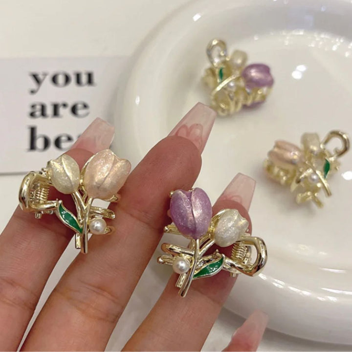 Goldene Blumenohrringe mit Perlen und lila Details auf weißem Hintergrund.