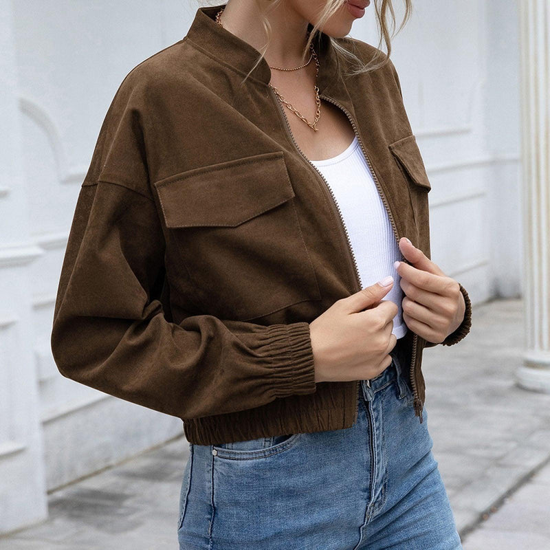 Frau in brauner Wildlederjacke, weißem Top und blauer Jeans, modisch, lässig, urbaner Stil.