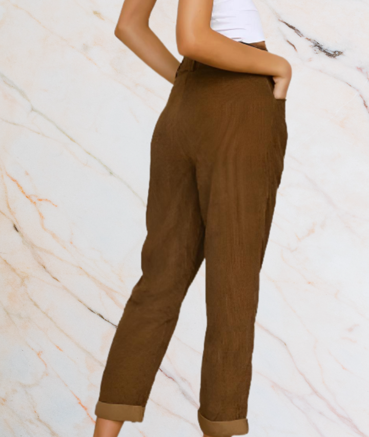 Frau in brauner Leinenhose vor Marmorhintergrund, modisch, elegant, lässig.