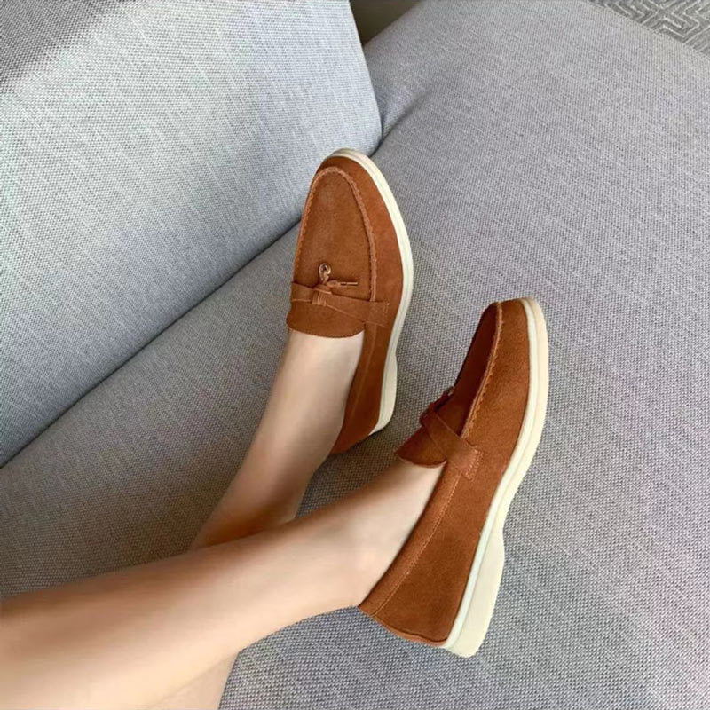 Braune Wildleder-Loafer für Damen, bequem, modisch, auf grauem Sofa.
