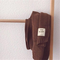 Brauner Strickschal aus Wolle, hängend, mit Etikett "Bonbon", modisch und warm.