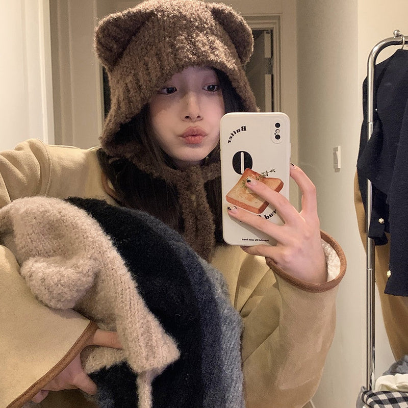 Frau mit braunem Bärenmütze, Selfie, beige Mantel, Wintermode, Handyhülle, Spiegelbild.