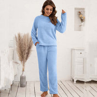 Frau in hellblauem Fleece-Pyjama-Set, gemütlich, langärmelig, Innenraum, Schlafzimmer.