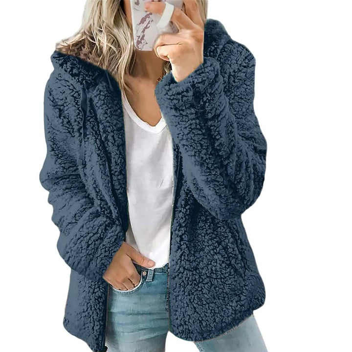 Frau in blauer Teddyfelljacke, weißem T-Shirt und Jeans, modische Winterbekleidung.