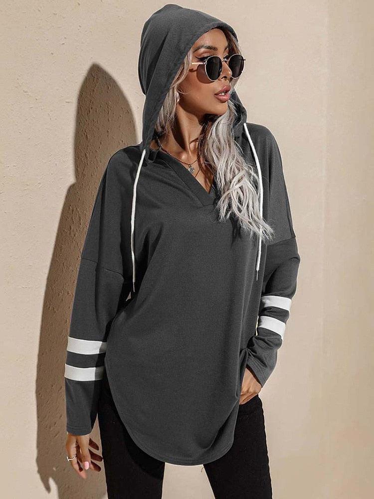 Frau in grauem Kapuzenpullover mit Streifen, Sonnenbrille, lässige Mode, Herbstoutfit.