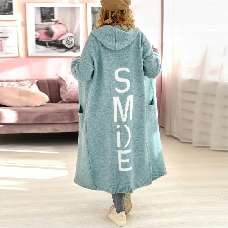 Frau in blauem Kapuzenmantel mit "SMILE"-Aufdruck, lässige Mode, Wohnzimmer.