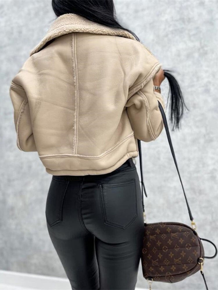 Frau in beiger Lederjacke, schwarze Hose, braune Designer-Handtasche, Rückansicht.