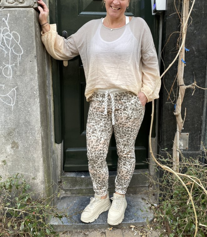 Frau in beiger Bluse und Leopardenhose vor Tür, lässiger Look, Mode, Streetstyle.