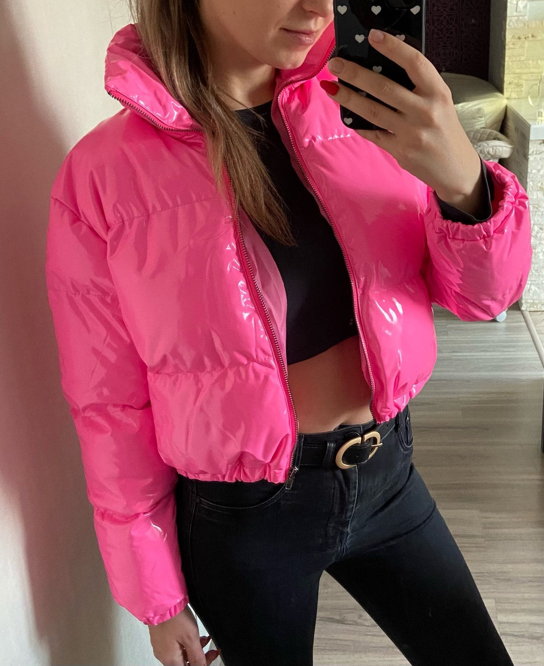 Frau in pinker Daunenjacke, schwarzes Top, Jeans, Selfie, modisch, Winterkleidung.