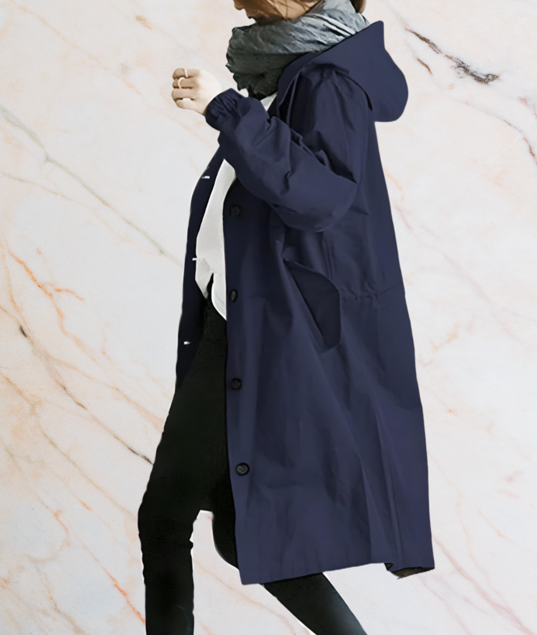 Frau im dunkelblauen Regenmantel mit Kapuze, grauer Schal, Marmorhintergrund.