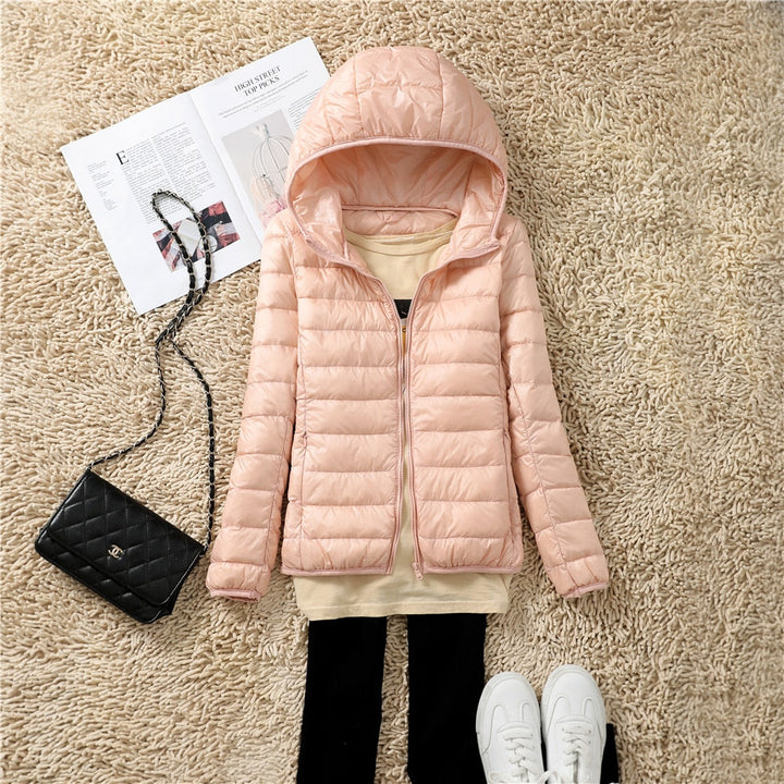 Damen Steppjacke rosa mit Kapuze, modisch, warm, Herbst Winter, auf Teppich mit Tasche und Zeitschrift.