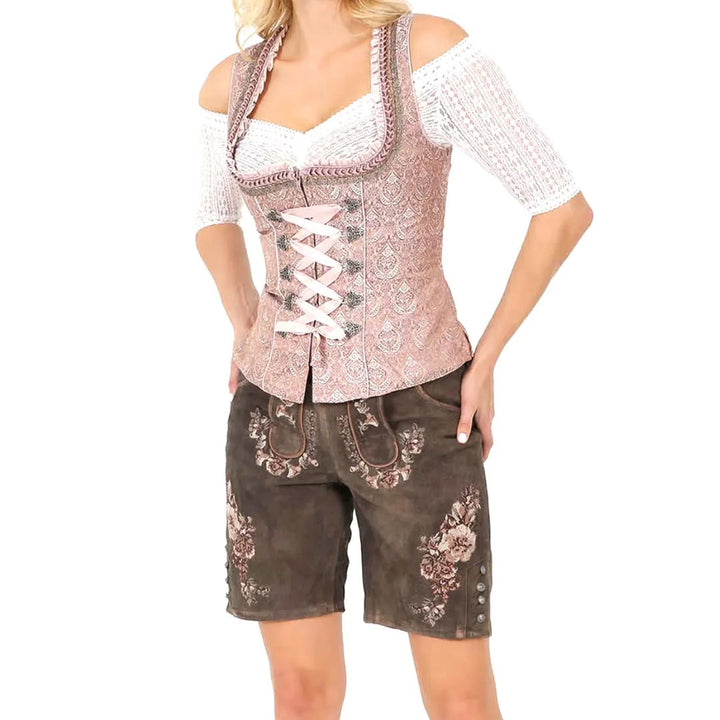 Frau in rosa Brokat-Dirndl mit weißer Bluse und brauner Lederhose, traditionell, elegant.