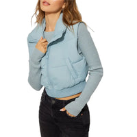 Frau in hellblauer Steppweste, langärmliges Oberteil, schwarze Jeans, modisch, Herbstkleidung.