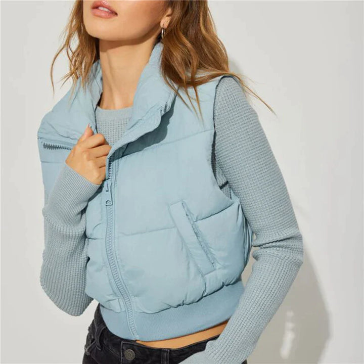 Frau trägt hellblaue Steppweste, Strickpullover, modisch, Herbstmode, Damenbekleidung.